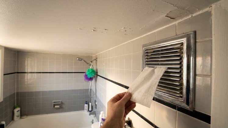 Tissue held to a bathroom exhaust fan grille to test airflow