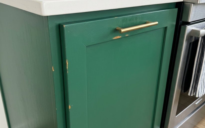 Why Is My Paint Chipping? Poor Prep or Surface Used to Soon? 3 Chipped green paint along a kitchen cabinet door edge and below the handle, showing the old finish underneath