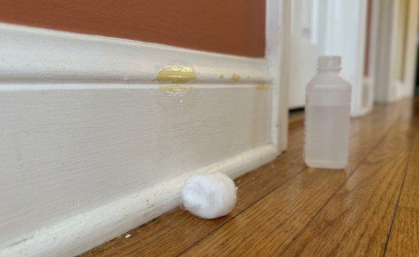 Why Is My Paint Chipping? Poor Prep or Surface Used to Soon? 2 Cotton ball and bottle of rubbing alcohol on the floor beside chipped baseboard trim