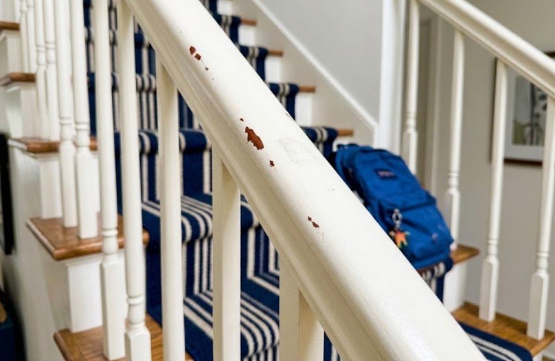 Why Is My Paint Chipping? Poor Prep or Surface Used to Soon? 5 Painted white stair railing with chips showing dark stained wood where hands grip it daily