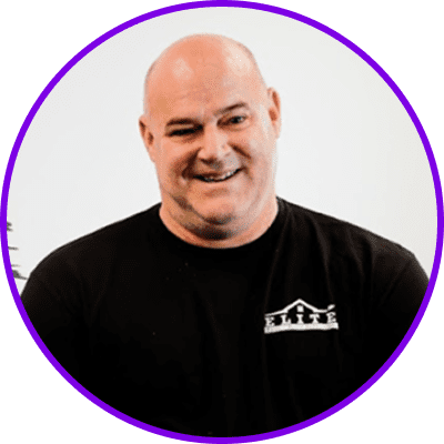 Home 26 Bald man in a black shirt with a logo, smiling, framed in a purple circle.