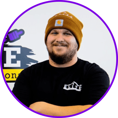 Home 27 A person in a brown beanie and black t-shirt with crossed arms, logo background visible.