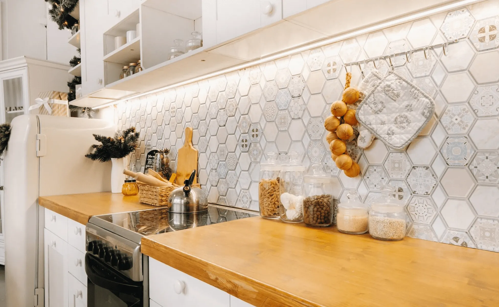 Well-organized kitchen with wooden countertop, white cabinets, and hexagonal tile backsplash.