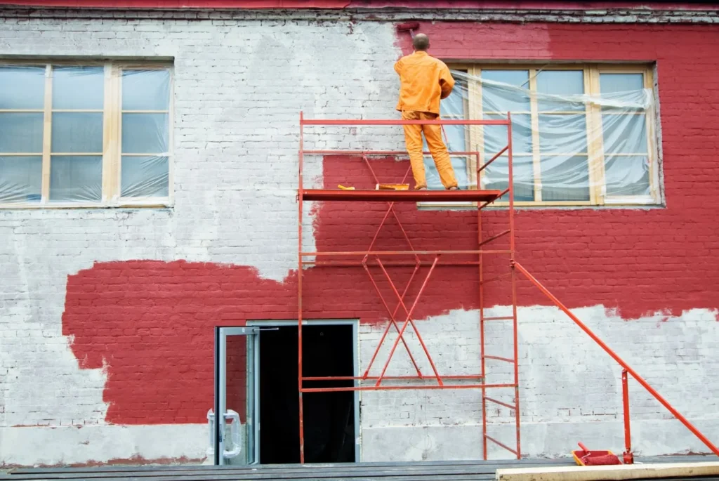 Best Practices for Maintaining Painted Exteriors in Harrison Township 4 a man standing on a scaffolding outside of a building