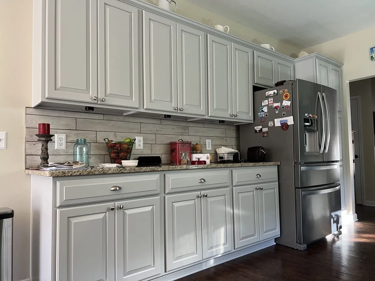 a kitchen with white cabinets and a stainless steel refrigerator