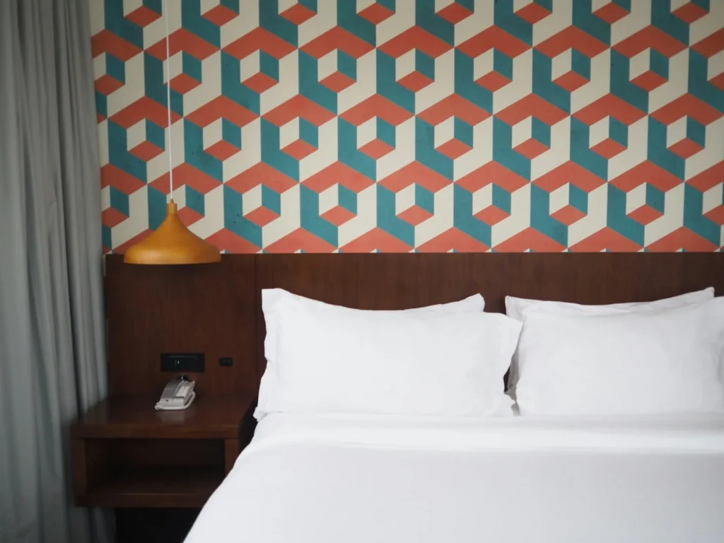 Wallpaper vs. Paint: Making the Right Choice for Your Home’s Interior 7 a bed with white sheets and a lamp on a table