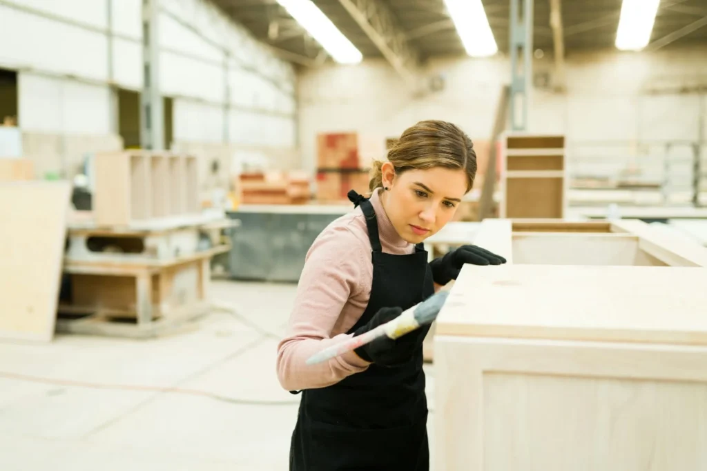 a woman in an apron painting a cabinet