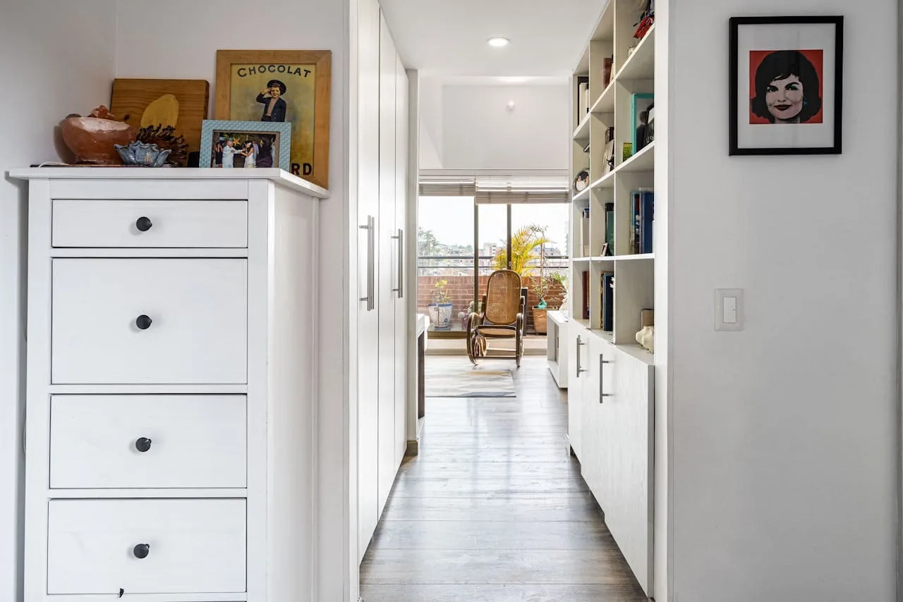a hallway with white cabinets and shelves